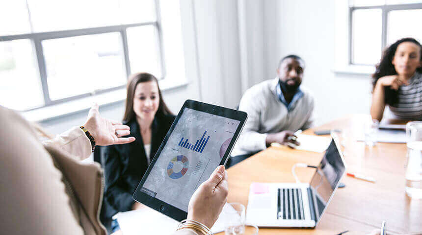 hands holding a tablet with a table and graph on at a business meeting